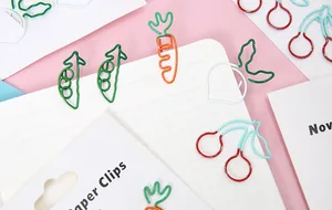 Nahaufnahme von kreativen Briefklammern in Obst- und Gemüseform auf Karopapier