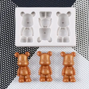 Close-up of white silicone mold with three finished golden bear-shaped resin figures