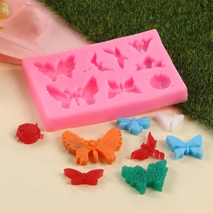Vue détaillée du moule en silicone papillon et insecte avec des formes en fondant colorées.