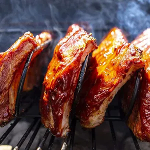 Close-up of a durable stainless steel rib rack holding glazed BBQ ribs on a smoking grill