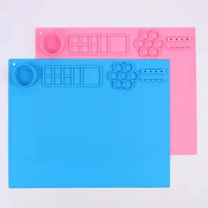 Vista dall'alto di tappetini in silicone rosa e blu con tavolozze e supporti integrati