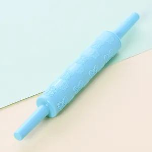 Detailed view of light blue plastic rolling pin with embossed butterfly patterns.