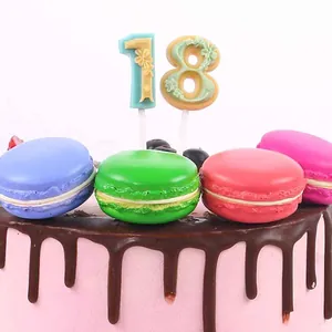 Primer plano de piruletas decorativas de chocolate número 18 sobre una tarta de macarons vivos