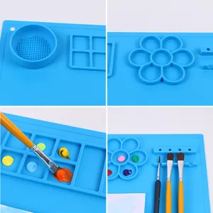 Primo piano di un tappetino per pittura in silicone blu con tavolozze e pennelli vari