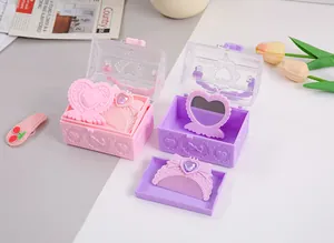 Nahaufnahme von herzförmigen Schatzkästchen mit Spiegeln und Kämmen in Pink und Lila.