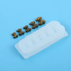 Detail of mini bear silicone mold with five metallic bronze bear charms on blue background