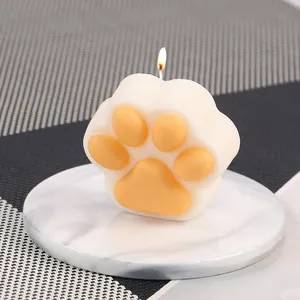 Primer plano de vela con forma de pata de gato sobre una bandeja de mármol blanco