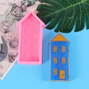 House-shaped pink silicone mold and blue glittery finished craft sample on blue background