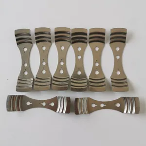 Close-up of eight stainless steel three-hole candle wick centering tools on white background