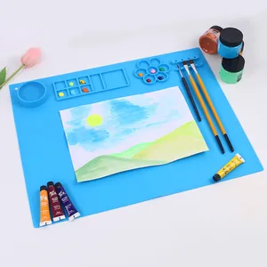 Vista dettagliata di un tappetino per pittura in silicone blu con tavolozze e pennelli.
