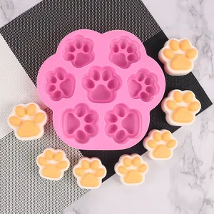 Molde de silicona rosa con siete cavidades de pata de gato y muestras de cera hechas