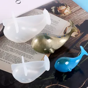 Nahaufnahme von 3D-Wal-Silikonformen und glitzernden Harzwal-Ornamenten für DIY-Bastelarbeiten