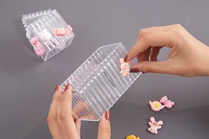 Primo piano di mani che decorano una scatola trasparente con simpatici ciondoli fai-da-te