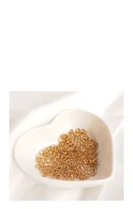 Vue macro d'anneaux de jonction ouverts en or 14 carats pour bijoux DIY dans un plat cœur