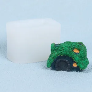 Dettaglio di uno stampo in silicone a forma di casa con una candela a casetta verde muschio.