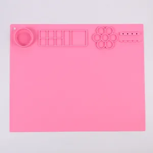 Vista dettagliata del tappetino per pittura in silicone rosa con tavolozza e porta pennelli