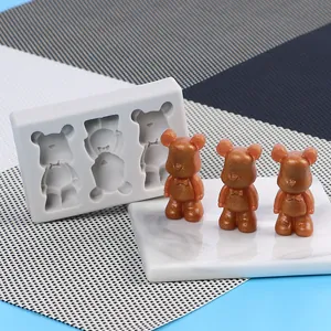 Detailed macro view showing a mini bear silicone mold alongside three finished glitter figurines