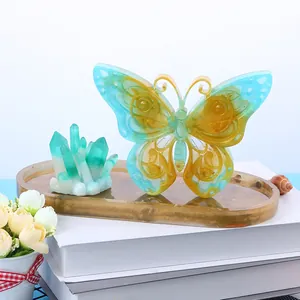 Dettaglio di un ornamento a farfalla in resina fai-da-te e cristalli su vassoio d'oro.