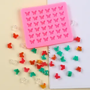 Détail du moule en silicone papillon rose avec des pièces miniatures colorées.