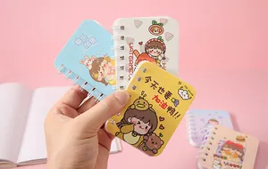 Close-up of cute cartoon mini spiral notebooks held in hand showing portable pocket size