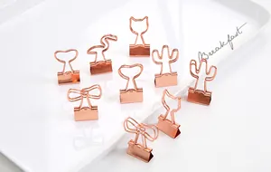 Detailansicht kreativer roségoldener Metallklammern in Tier- und Schleifenform