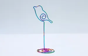 Close-up detail of rainbow-colored metal wire memo clip in a cute bird shape design for photos