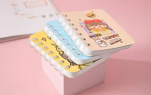 Stack of cute cartoon mini spiral notebooks with colorful cover designs on pink background.