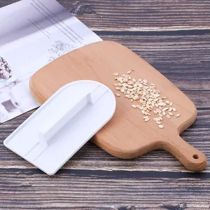 Dettaglio del levigatore per fondente in plastica bianca con impugnatura su tagliere