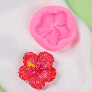 Detailed view of pink flower silicone mold next to a finished red resin hibiscus piece