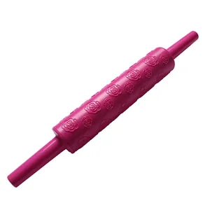 Detailed view of the embossed rose pattern on a pink plastic fondant rolling pin