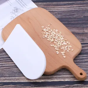 Raschietto per dolci bianco in plastica su un tagliere di legno