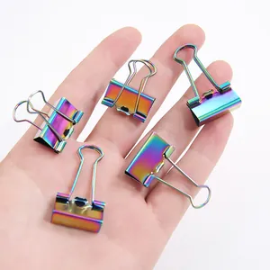 Set mit fünf regenbogenfarbenen Metall-Bindeklammern auf einer Hand vor weißem Hintergrund