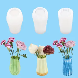 Detail of three geometric silicone molds and finished resin vases in green yellow and blue