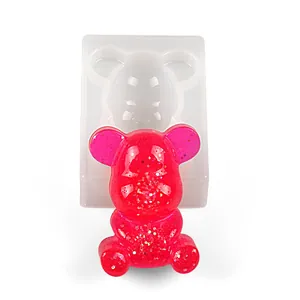 Close-up of a mini gummy bear silicone mold and a finished red glitter resin bear
