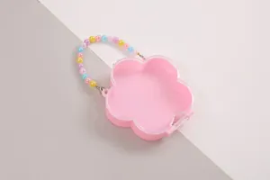 Nahaufnahme einer niedlichen rosa blumenförmigen Aufbewahrungsbox mit bunter Perlenkette