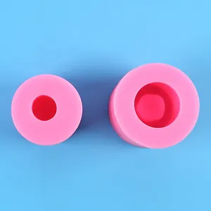 Top view of two pink cylindrical silicone molds for DIY candle making on blue background