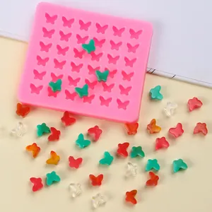 Gros plan de moule en silicone papillon avec décorations de fondant colorées sur le fond