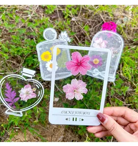 Detailed view of a hand holding a transparent DIY dried flower bookmark sticker