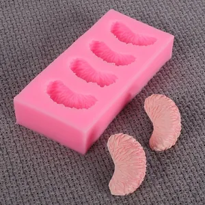 Pink silicone orange segment mold with finished fondant pieces on grey textured cloth