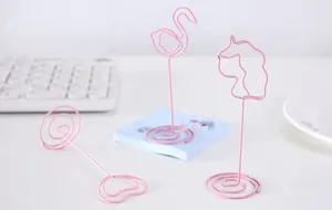 Creative pink metal wire memo holders in cute flamingo and unicorn shapes on a desk