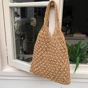 Bolso de playa de macramé tejido a mano colgado en una ventana blanca durante el verano