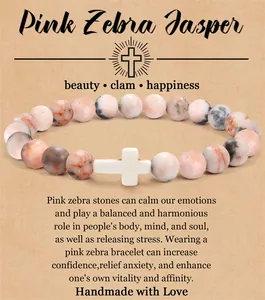 Natuurlijke roze zebra jaspis kralen armband met een witte kruis bedel op een cadeaukaartje