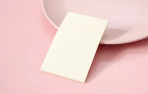 Close-up of semi-transparent sticky notes on a minimalist pink plate and background.