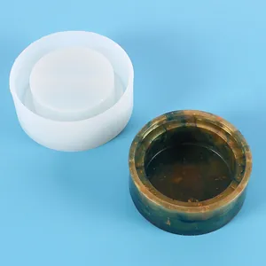 Close-up of a circular silicone mold alongside a finished marbled resin storage container