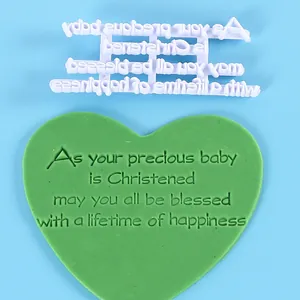 Detailopname van hartvormige fondant met een reliëftekst voor een baby-doopzegening.