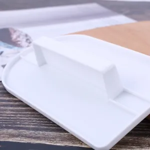 Primo piano di una spatola lisciante per pasta di zucchero in plastica bianca con impugnatura.