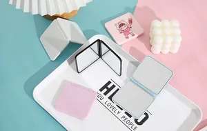 Detail shot of various colorful portable folding makeup mirrors on a decorative tray