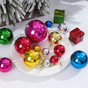 Detailansicht bunter galvanisierter Weihnachtskugeln auf einer weißen Dekoplatte.