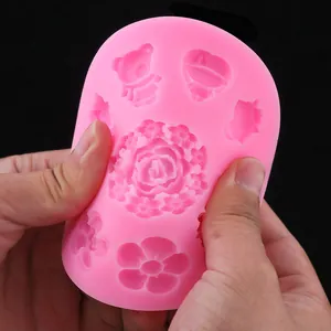 Close-up of flexible pink silicone mold showing various flower and character shapes.