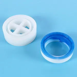 Close-up of a round silicone resin mold beside a finished blue and white craft ring.